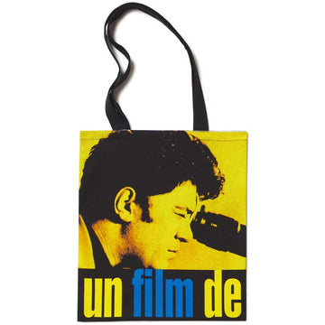 A yellow and black tote bag featuring a graphic print of a person's profile and the text 'un film de' in blue. Pedro Almodovar director tote bag